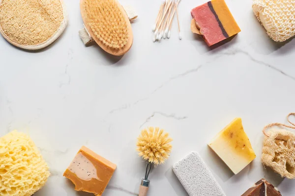 Top view of homemade soap, pumice stone, bath sponges, ear sticks and body brushes on marble surface — Stock Photo