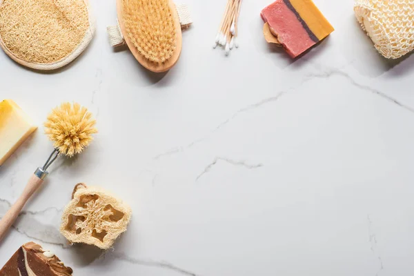 Vista dall'alto di auricolari, spugne da bagno, sapone, loofah e spazzole per il corpo sulla superficie di marmo — Foto stock