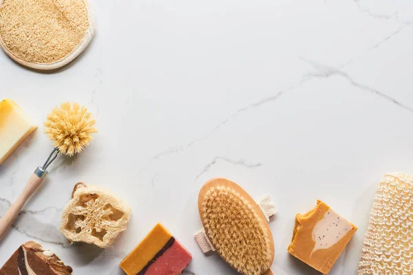 Top view of homemade natural soap, loofah, bath sponges and body brushes on marble surface with copy space — Stock Photo