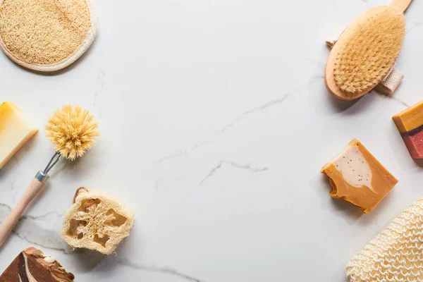 Top view of loofah, bath sponges, body brushes and soap pieces on marble surface with copy space — Stock Photo