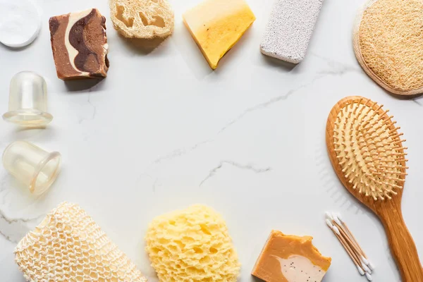 Vista dall'alto di vasetti per massaggi, spazzola per capelli, spugna da bagno, loofah e pietra pomice sulla superficie di marmo — Foto stock