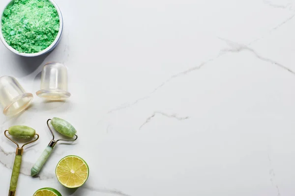 Vue de dessus des bocaux de massage et des rouleaux près des sels de bain et de la chaux sur la surface du marbre — Photo de stock