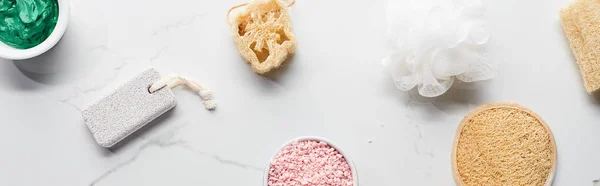 Plan panoramique des éponges de bain, loofah, pierre ponce et tasses avec des produits de beauté naturels sur la surface du marbre — Photo de stock