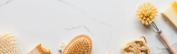 Panoramic shot of loofah, body brushes, soap and bath sponge on marble surface — Stock Photo