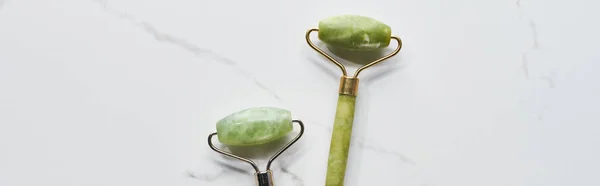 Panoramic shot of jade facial rollers on marble surface — Stock Photo