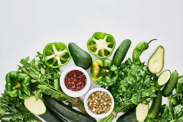 Top view of pumpkin seeds, spices, avocados, cucumbers, peppers, greenery and zucchini — Stock Photo