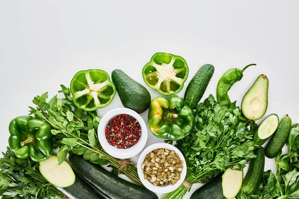 Vue de dessus des graines de citrouille, épices, avocats, concombres, poivrons, verdure et courgettes — Photo de stock