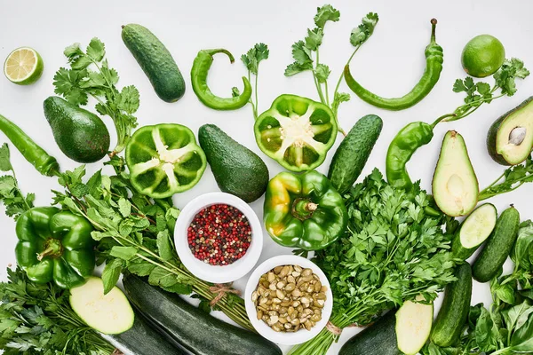 Top view of pumpkin seeds, avocados, cucumbers, limes, peppers, spices, greenery and zucchini — Stock Photo