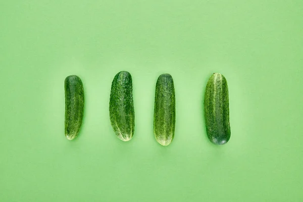 Vue de dessus des concombres frais et entiers sur fond vert — Photo de stock