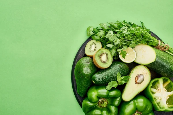 Top view of avocados, peppers, kiwi, lime, zucchini and greenery on pizza skillet — Stock Photo