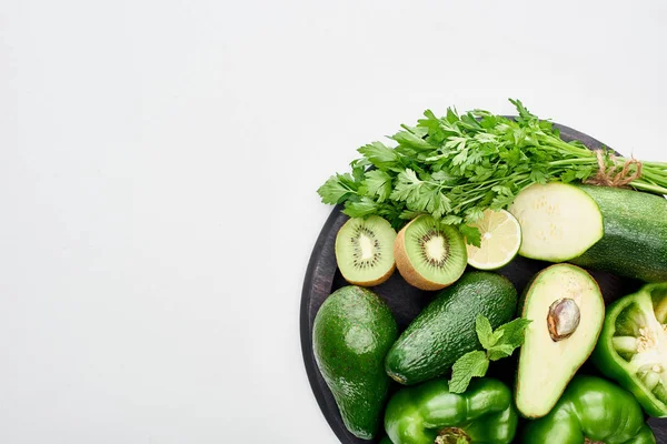 Top view of avocados, peppers, kiwi, lime, zucchini and greenery on pizza skillet — Stock Photo