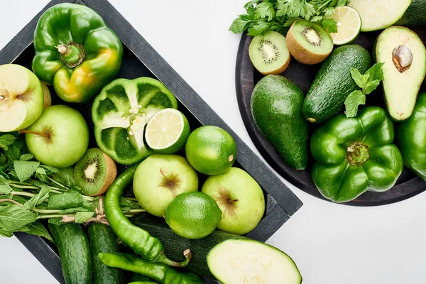 Vista superior de abacates, pimentas, kiwi, maçãs, limas, abobrinha e vegetação em frigideira e caixa de pizza — Fotografia de Stock