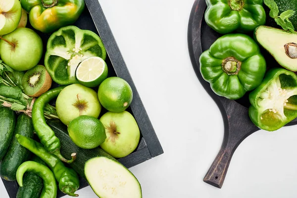 Vista superior de aguacate, pimientos, kiwi, manzanas, limas, calabacín y vegetación en la sartén y caja de pizza - foto de stock