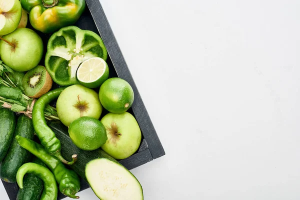 Top view of apples, limes, peppers, kiwi, cucumbers and zucchini in wooden box — Stock Photo