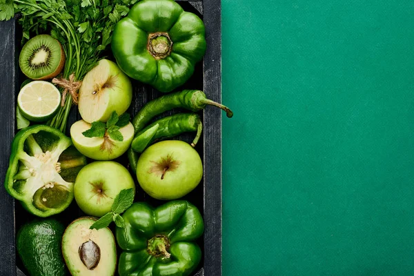 Top view of apples, lime, avocados, peppers, kiwi, greenery in box — Stock Photo