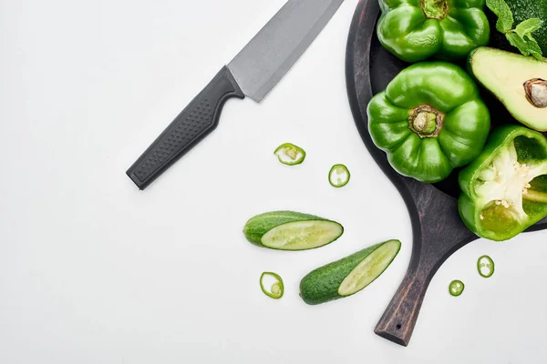 Top view of knife, avocado, peppers, cucumbers and greenery on pizza skillet — Stock Photo