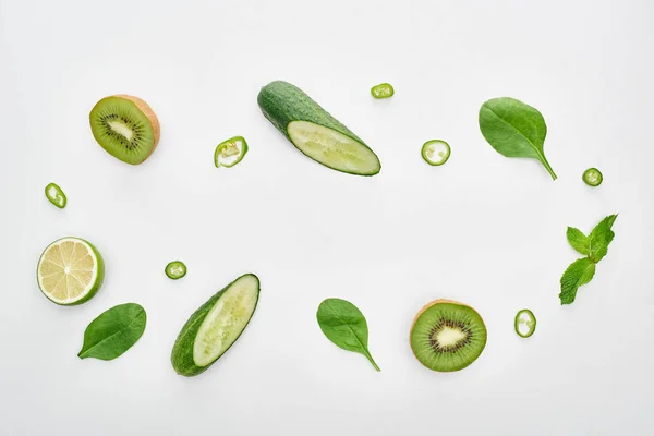 Top view of cut cucumbers, kiwi, lime, peppers and greenery — Stock Photo