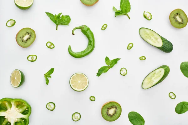 Top view of fresh cucumbers, kiwi, limes, peppers and greenery — Stock Photo