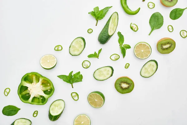 Top view of fresh cucumbers, kiwi, limes, peppers and greenery — Stock Photo
