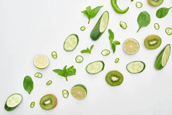 Top view of fresh cucumbers, kiwi, limes, peppers and greenery — Stock Photo