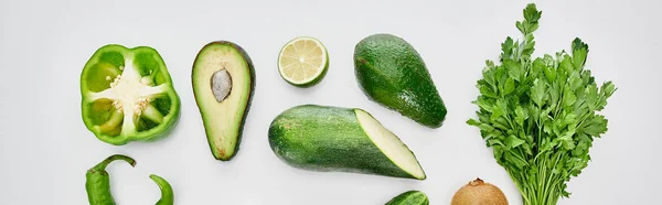 Panoramic shot of peppers, zucchini, kiwi, lime, greenery and avocados — Stock Photo