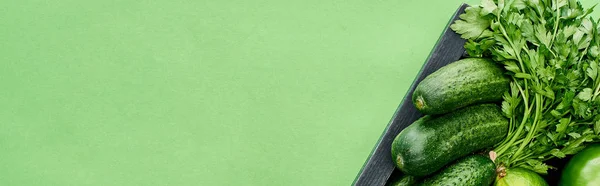 Панорамный снимок цельных огурцов и зелени в деревянной коробке — стоковое фото