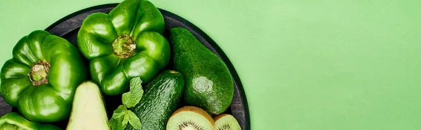 Panoramic shot of avocados, peppers, kiwi and greenery on pizza skillet — Stock Photo