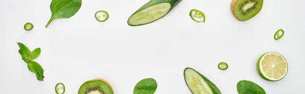 Panoramic shot of fresh cucumbers, kiwi, lime, peppers and greenery — Stock Photo