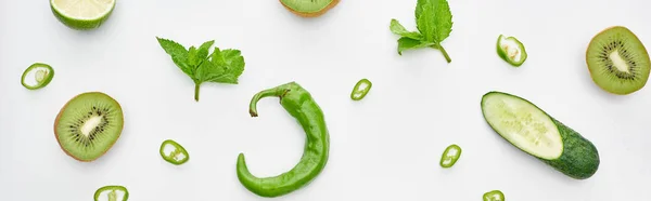 Panoramic shot of fresh cucumber, kiwi, lime, peppers and greenery — Stock Photo