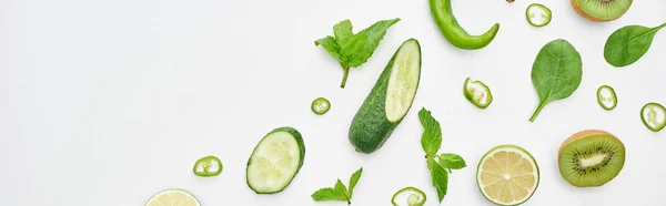 Coup panoramique de concombres frais, kiwi, citrons verts, poivrons et verdure — Photo de stock