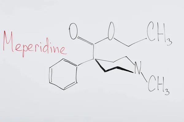 Top view of white board with chemical formula and lettering meperidine — Stock Photo
