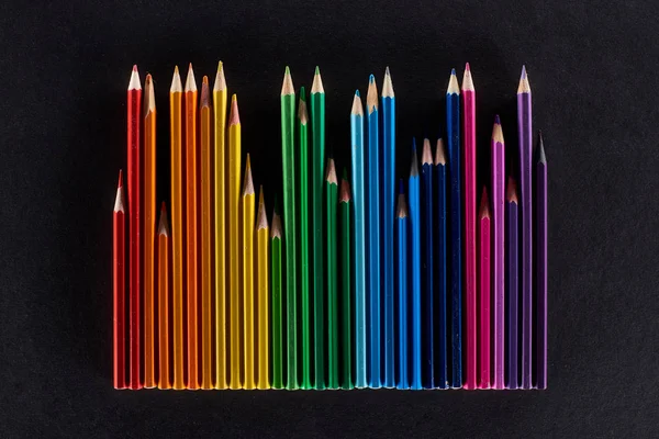 Spectre arc-en-ciel composé de crayons de couleur isolés sur du noir — Photo de stock