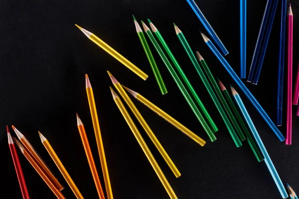Scattered sharpened color pencils isolated on black — Stock Photo