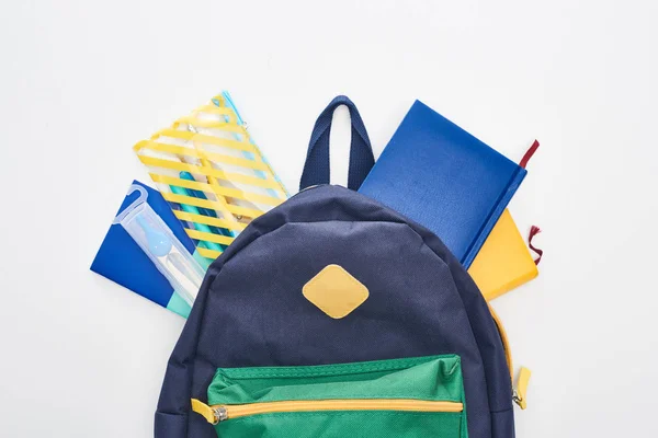 Sac scolaire bleu avec différentes fournitures scolaires isolées sur blanc — Photo de stock