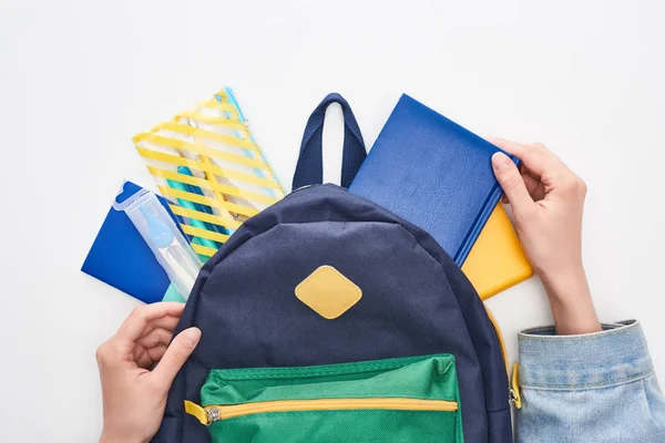 Bolso escolar azul con bloc de notas y estuche de lápiz en manos de colegiala aislada en blanco - foto de stock