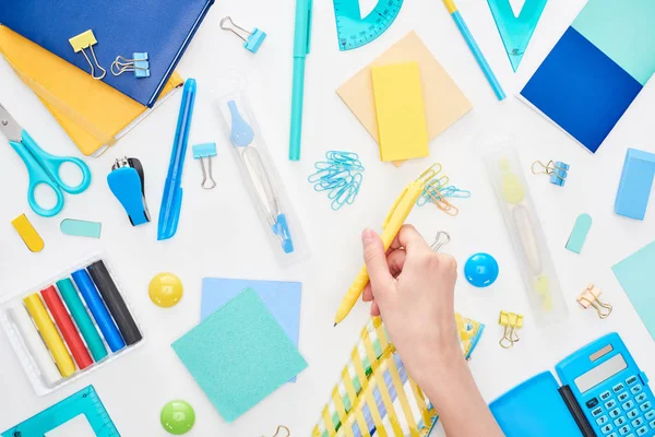 Cropped image of schoolgirl holding yellow pen near stationery isolated on white — Stock Photo