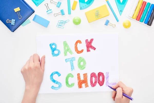 Immagine ritagliata di scolaretta che scrive su scheda con testo di ritorno a scuola isolato su bianco — Foto stock