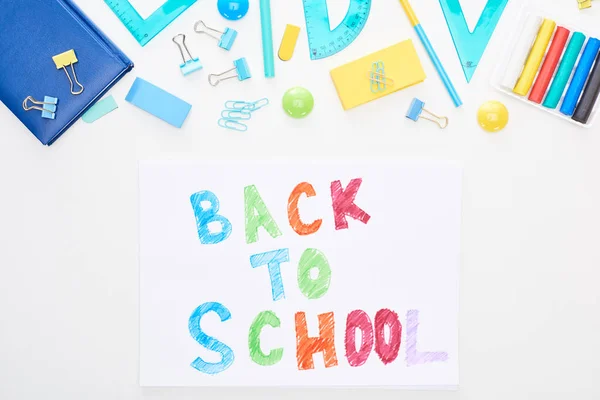 Top view of paper with back to school text near school supplies isolated on white — Stock Photo
