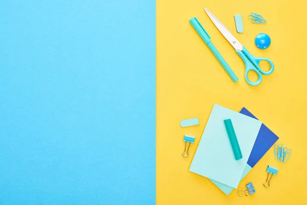 Vista dall'alto di diversi articoli di cancelleria blu con fogli di carta su sfondo bicolore — Foto stock