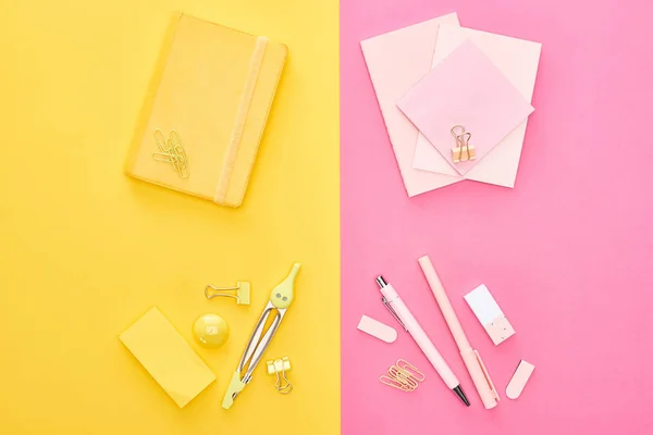 Top view of yellow notepad and pink sheets of paper with different stationery on bicolor background — Stock Photo