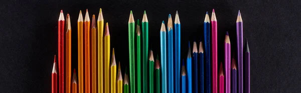 Vue panoramique du spectre arc-en-ciel réalisée avec une rangée droite de crayons de couleur isolés sur du noir — Photo de stock