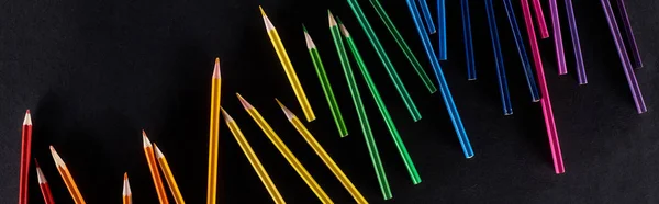 Plan panoramique du gradient arc-en-ciel réalisé avec des crayons de couleur aiguisés isolés sur du noir — Photo de stock