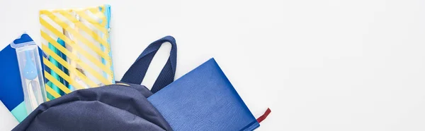 Colpo panoramico di schoolbag blu con taccuini, astuccio e materiale scolastico isolato su bianco — Foto stock