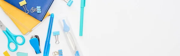 Panoramic shot of blue and yellow scattered school supplies isolated on white — Stock Photo