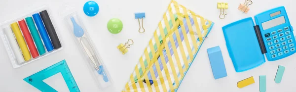 Panoramic shot of blue and yellow scattered school supplies with pencil case and calculator isolated on white — Stock Photo