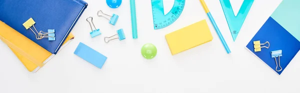 Panoramic shot of blue and yellow scattered school supplies with notepads and pencil case isolated on white — Stock Photo