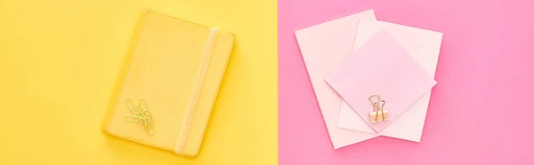 Foto panorámica de bloc de notas amarillo y hojas de papel rosa sobre fondo bicolor - foto de stock