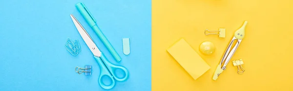 Foto panorámica de diferentes artículos de papelería azules y amarillos sobre fondo bicolor - foto de stock