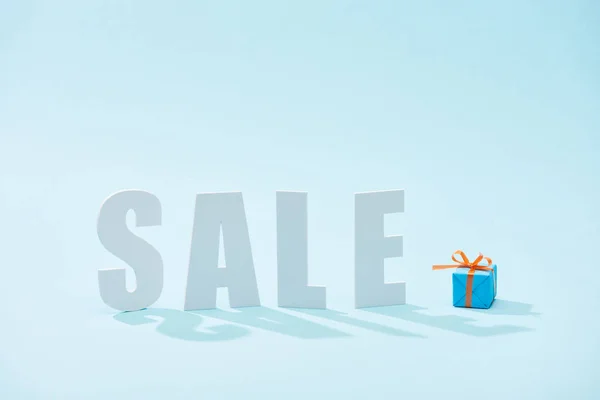 Scritta di vendita bianca e scatola regalo festivo su sfondo blu — Foto stock