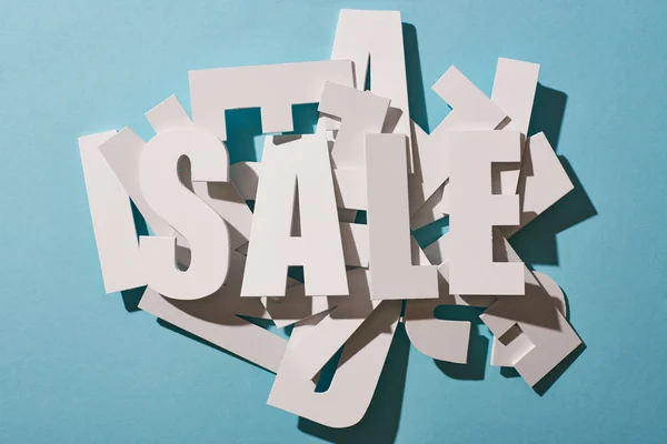 Top view of white sale lettering on pile of letters on blue background — Stock Photo